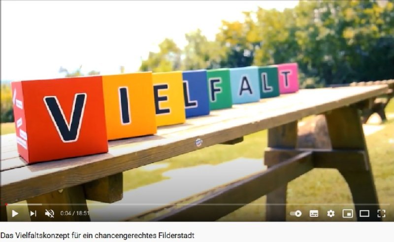 Das Bild zeigt 8 farbige Würfel. Jeder Würfel hat einen Buchstaben. Zusammengesetzt ergibt sich das Wort "Vielfalt". Das Bild ist mit dem Youtube-Kanal der Stadt Filderstadt verknüpft.