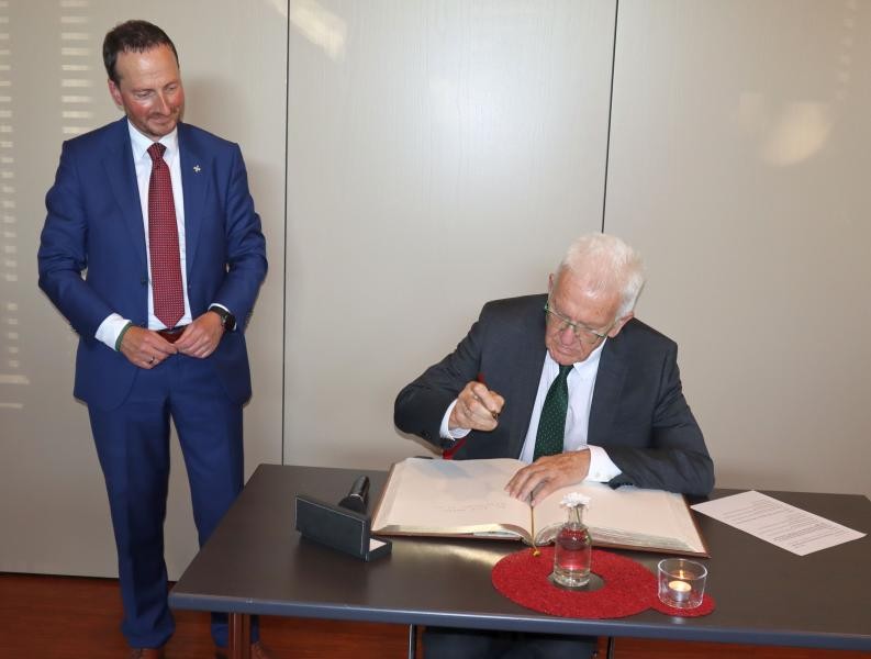Ministerpräsident Winfried Kretschmann trägt sich ins Goldene Buch der Stadt ein und Oberbürgermeister Christoph Traub  schaut ihm dabei zu. 