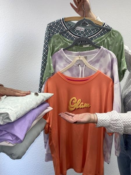 Kleider auf Bügeln und Wäschestapeln mit Händen, die geben und nehmen