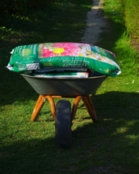 Schubkarre auf dem ein Sack mit Erde liegt