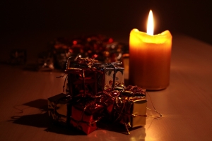 Kleine Geschenke liegen um eine brennende Kerze