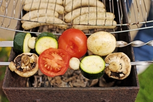 Grill auf dem Würste und unterschiedliche Gemüsesorten liegen